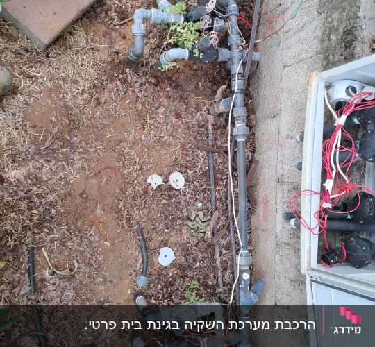 מערכת השקיה עם צינורות ושסתומים בגינה